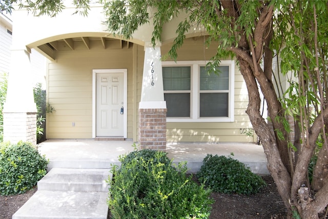 view of exterior entry featuring brick siding and covered porch