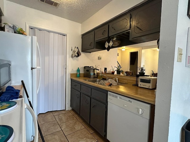 kitchen with wood counters, dishwasher, sink, dark brown cabinets, and a textured ceiling