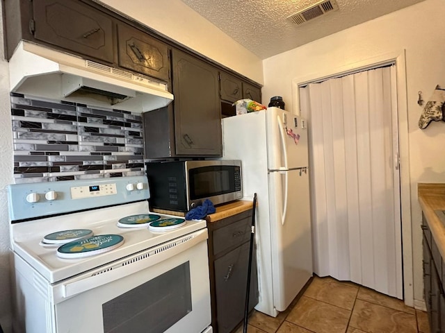 kitchen with butcher block counters, light tile patterned floors, white appliances, dark brown cabinetry, and a textured ceiling