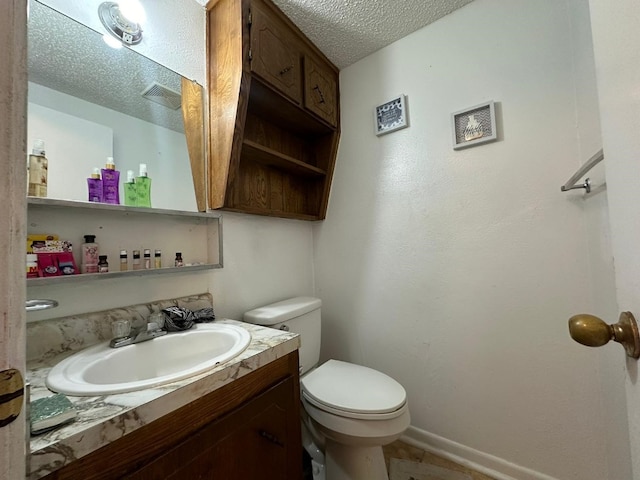 bathroom with vanity, toilet, and a textured ceiling