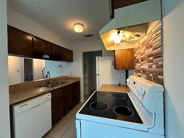 kitchen with sink, white appliances, dark brown cabinets, a textured ceiling, and light tile patterned flooring