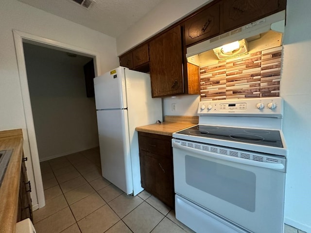 kitchen with light tile patterned flooring, white appliances, dark brown cabinetry, and a textured ceiling