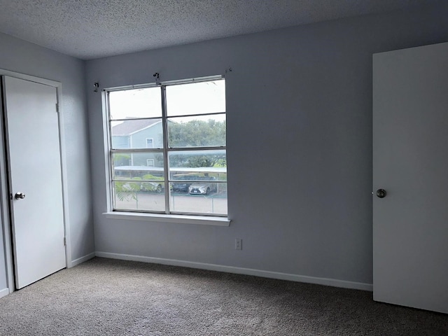 carpeted empty room featuring a textured ceiling