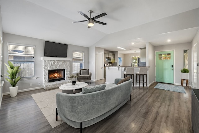 living room with a stone fireplace, dark hardwood / wood-style flooring, and ceiling fan