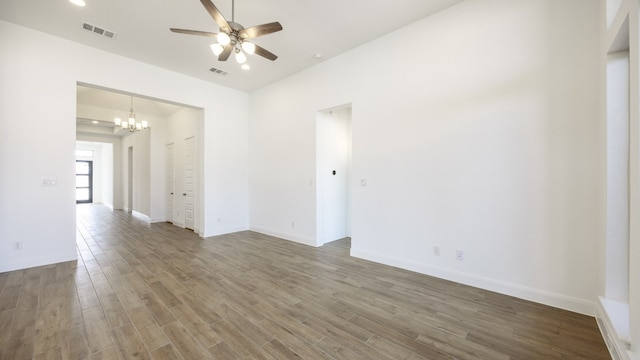 empty room with hardwood / wood-style floors and ceiling fan with notable chandelier