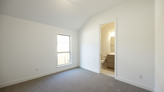 unfurnished bedroom featuring ensuite bathroom, light carpet, and lofted ceiling