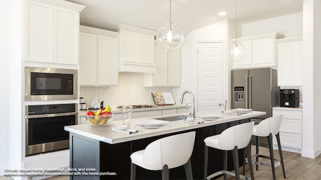 kitchen with light hardwood / wood-style flooring, stainless steel appliances, a center island with sink, sink, and white cabinets