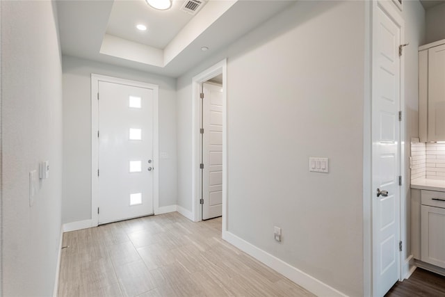 entrance foyer with a tray ceiling and light wood-type flooring