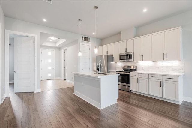 4507 E Martin Luther King Jr Blvd Unit 122, Austin, TX 78721 - kitchen with appliances with stainless steel finishes, a sink, decorative backsplash, a center island with sink, and white cabinets