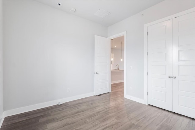 4507 E Martin Luther King Jr Blvd Unit 122, Austin, TX 78721 - unfurnished bedroom featuring wood finished floors, a closet, baseboards, and a sink
