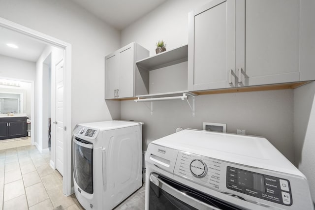 washroom featuring cabinet space, washer and clothes dryer, and light tile patterned flooring