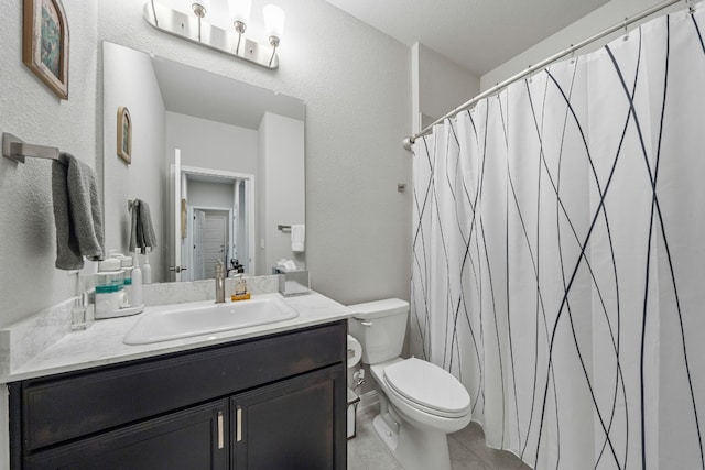 bathroom with toilet, tile patterned floors, a textured wall, and vanity