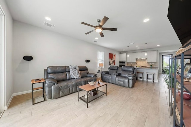 living room with light wood-style flooring, visible vents, a ceiling fan, and recessed lighting