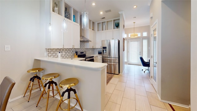 kitchen with appliances with stainless steel finishes, decorative backsplash, white cabinets, a kitchen bar, and decorative light fixtures