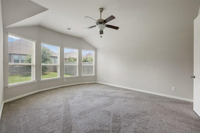 empty room with vaulted ceiling, ceiling fan, and carpet floors