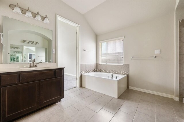 bathroom with a bathtub, tile patterned floors, vanity, and lofted ceiling