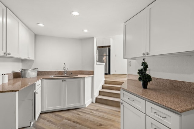 kitchen with freestanding refrigerator, light wood-style floors, recessed lighting, white cabinetry, and a sink