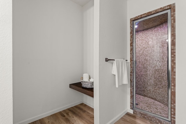 bathroom with baseboards, wood finished floors, and a shower stall