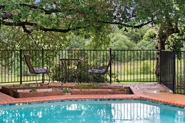 view of pool featuring a fenced in pool, a garden, and fence