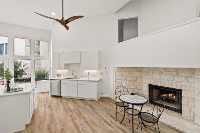 1 Crystal Springs Ct Unit G, The Hills, TX 78738 - kitchen featuring dishwasher, high vaulted ceiling, light countertops, white cabinets, and a fireplace