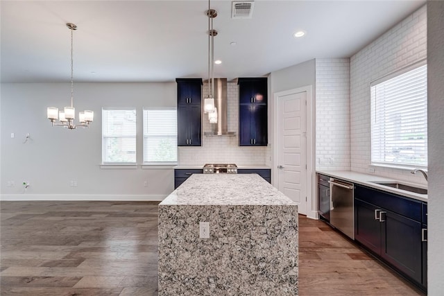 kitchen with decorative light fixtures, wood-type flooring, tasteful backsplash, dishwasher, and a kitchen island