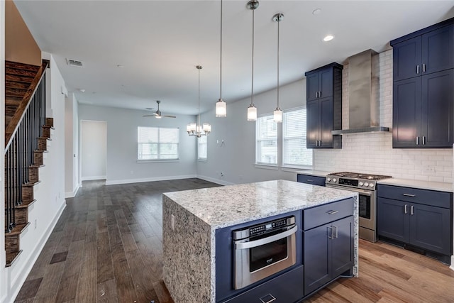 kitchen featuring a center island, visible vents, open floor plan, gas range, and wall chimney exhaust hood