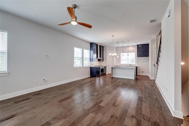 unfurnished living room featuring ceiling fan with notable chandelier and dark wood-type flooring