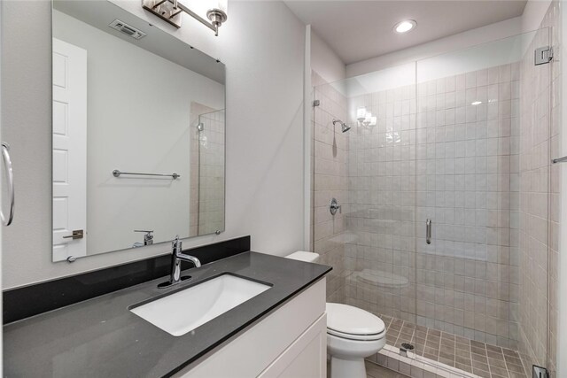 bathroom with vanity, toilet, and a shower with door