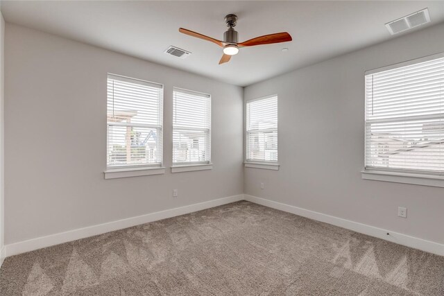 unfurnished room featuring light carpet, a wealth of natural light, and ceiling fan