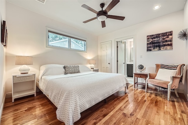 bedroom with ensuite bath, ceiling fan, and hardwood / wood-style flooring