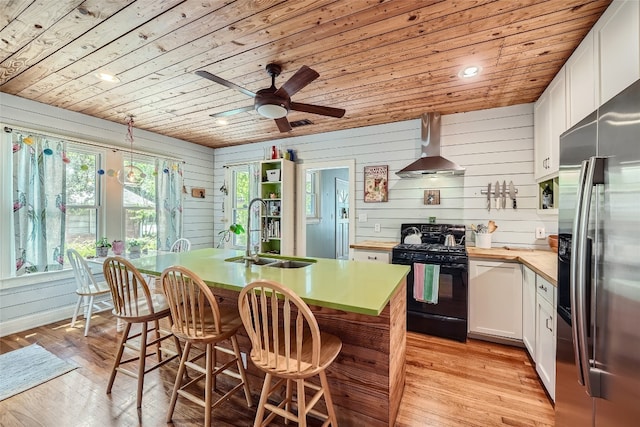 kitchen featuring light hardwood / wood-style flooring, stainless steel fridge, wall chimney range hood, wooden ceiling, and black range with gas cooktop