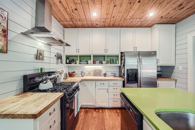 kitchen featuring wooden counters, light hardwood / wood-style flooring, wall chimney exhaust hood, range with two ovens, and stainless steel fridge