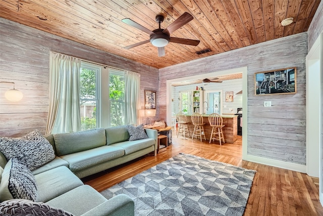 living room with wood ceiling, wooden walls, wood-type flooring, and a wealth of natural light