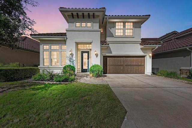 mediterranean / spanish-style home with a garage and a lawn