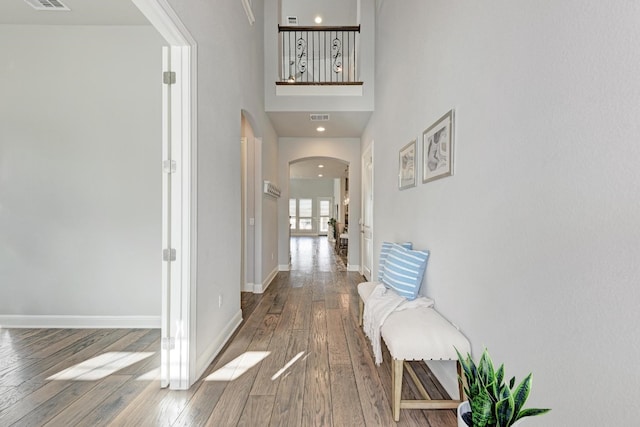 hall featuring hardwood / wood-style flooring and a towering ceiling