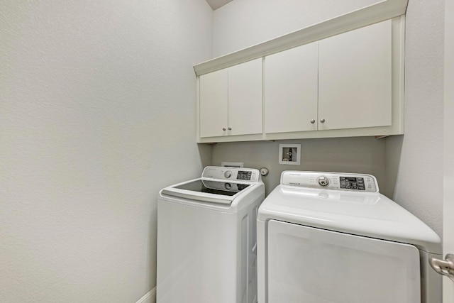 clothes washing area featuring separate washer and dryer and cabinets