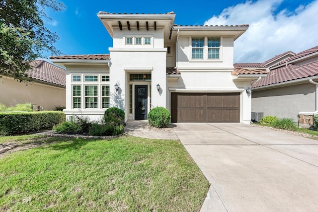 mediterranean / spanish home with a garage, central air condition unit, and a front yard