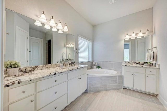 bathroom with tiled tub, tile patterned floors, and dual bowl vanity