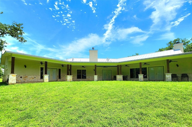 rear view of house featuring ceiling fan and a lawn