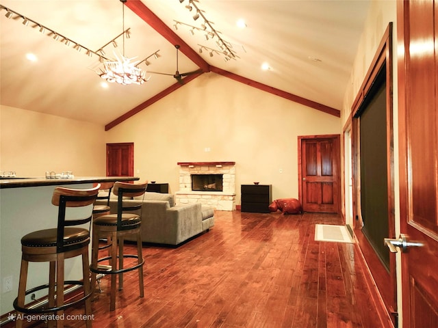 living room with high vaulted ceiling, hardwood / wood-style floors, a stone fireplace, and a notable chandelier