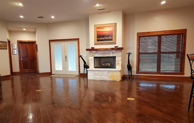 unfurnished living room with dark wood-type flooring, french doors, and a fireplace