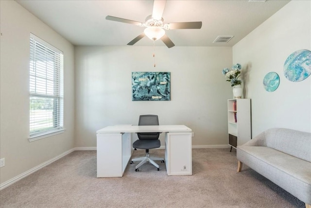 office space featuring light colored carpet, visible vents, ceiling fan, and baseboards