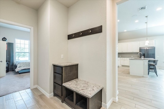 hall with light hardwood / wood-style floors and sink