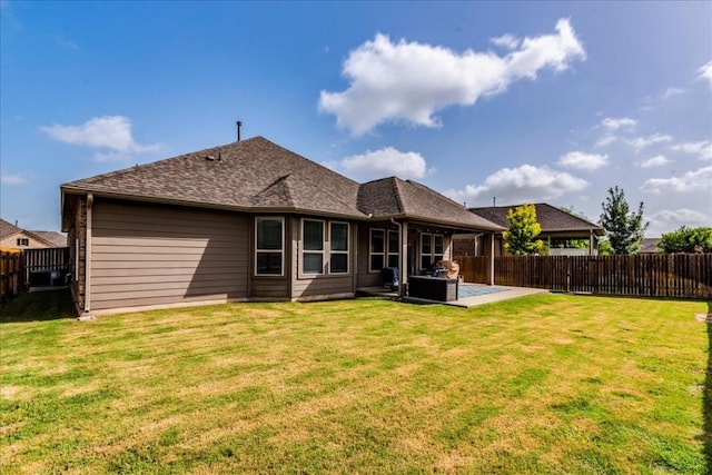 back of house with roof with shingles, a lawn, a patio area, and a fenced backyard