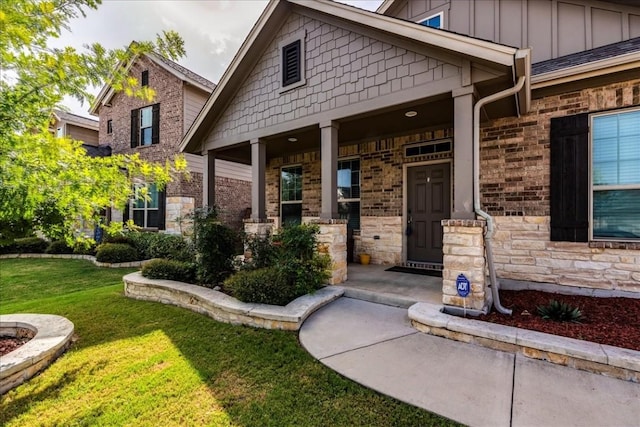 view of exterior entry with covered porch and a lawn