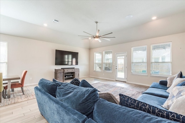 living room featuring lofted ceiling, light wood finished floors, baseboards, and visible vents