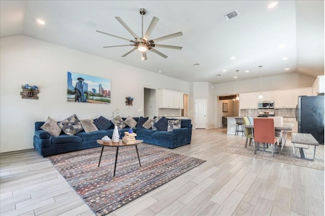 living room with vaulted ceiling, light hardwood / wood-style flooring, and ceiling fan