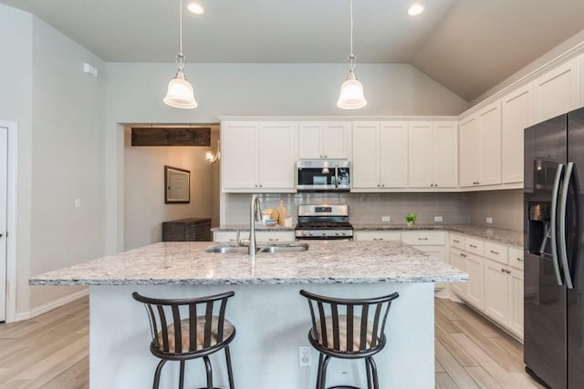 kitchen featuring tasteful backsplash, light wood-style flooring, vaulted ceiling, stainless steel appliances, and a sink