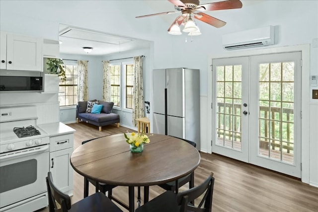 2108 River Hills Rd, Austin, TX 78733 - kitchen featuring appliances with stainless steel finishes, a wall mounted AC, light wood-style flooring, white cabinetry, and french doors