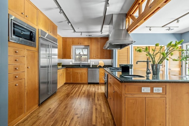 1202 E 30th St, Austin, TX 78722 - kitchen with track lighting, island exhaust hood, a sink, wood finished floors, and built in appliances